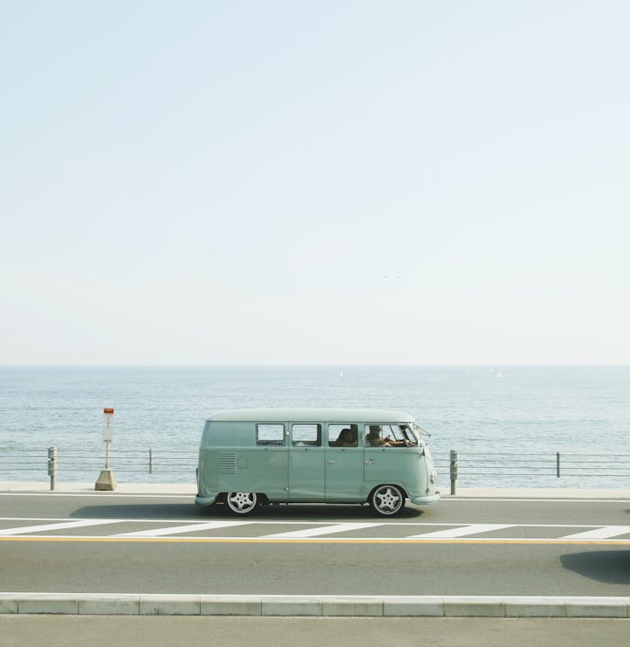 A classic Volkswagen van driving on a seaside road in Fujisawa, Japan, capturing a nostalgic coastal vibe.